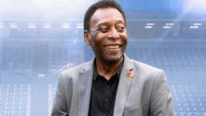 Pelé, o Rei do Futebol, em destaque sorrindo em uma foto recente, vestindo um terno cinza, representando a vida do Rei Pelé.