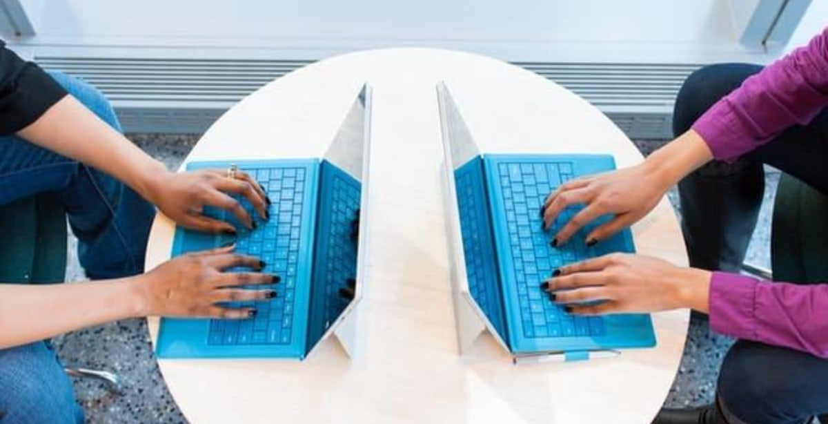 Duas pessoas trabalhando em laptops em um espaço compartilhado, representando colaboração em coworkings.