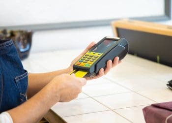 A imagem mostra uma pessoa realizando pagamento com seu cartão em uma máquina da PagBank.