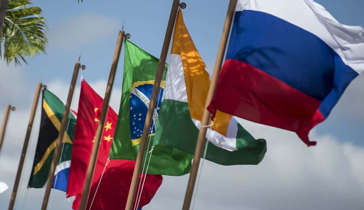 A imagem mostra as bandeiras dos baíses membros do BRICS tremulando por conta do vento.