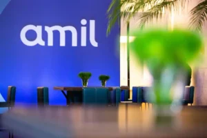 O investidor Nelson Tanure desiste de disputar a compra da Amil, citando exigências inviáveis do UnitedHealth Group. Bain Capital lidera favoritismo na transação.