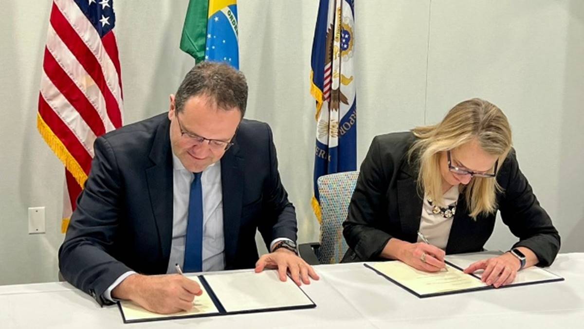 Nelson Barbosa, diretor do BNDES, à esquerda da imagem, e Sarah Fandell, vice-presidente e conselheira geral do DFC, banco americano, firmam acordo de cooperação internacional