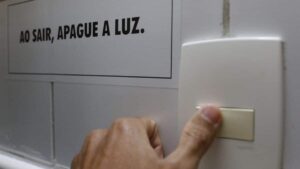 Imagem de uma tomada e uma mensagem ao lado "Ao sair, apague a luz" para representar a alta da prévia da inflação no Brasil.