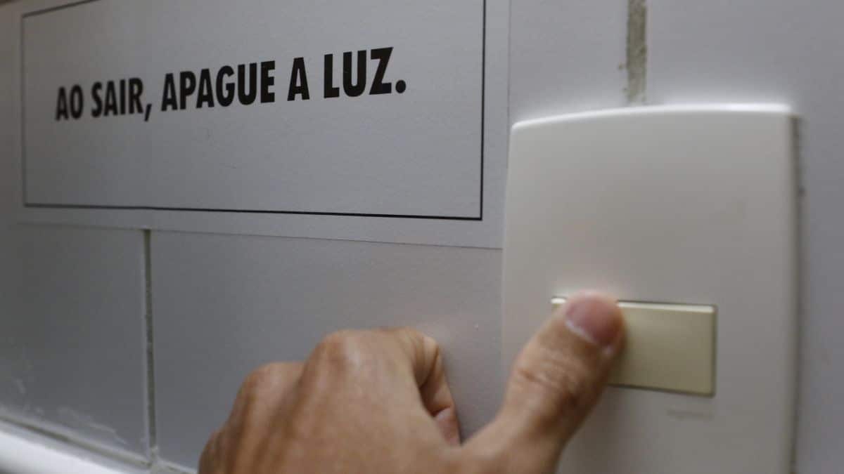 Imagem de uma tomada e uma mensagem ao lado "Ao sair, apague a luz" para representar a alta da prévia da inflação no Brasil.