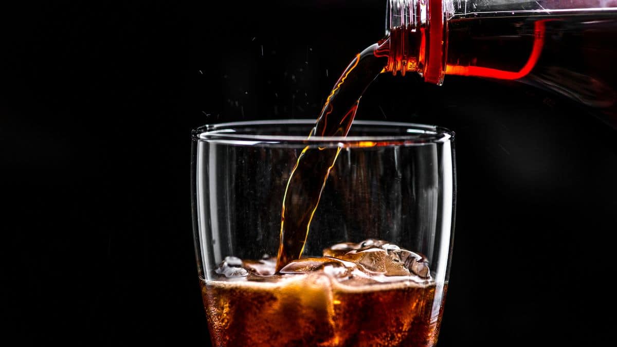 Imagem do refrigerante da Coca-Cola sendo colocado em um copo.