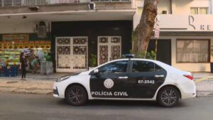 Imagem de um carro da Polícia Civil estacionado em frente a um prédio durante uma operação de combate ao golpe do falso sequestro.