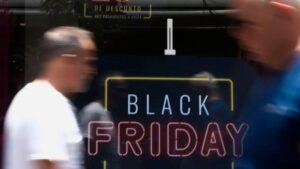 Imagem de uma fachada de uma loja em black friday e pessoas andando para ilustrar uma matéria jornalística sobre o Black Friday no Brasil.
