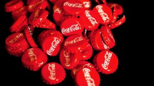 Imagem com várias tampinhas de Coca-Cola para ilustrar uma matéria jornalística sobre o investimento da Solar Bebidas.
