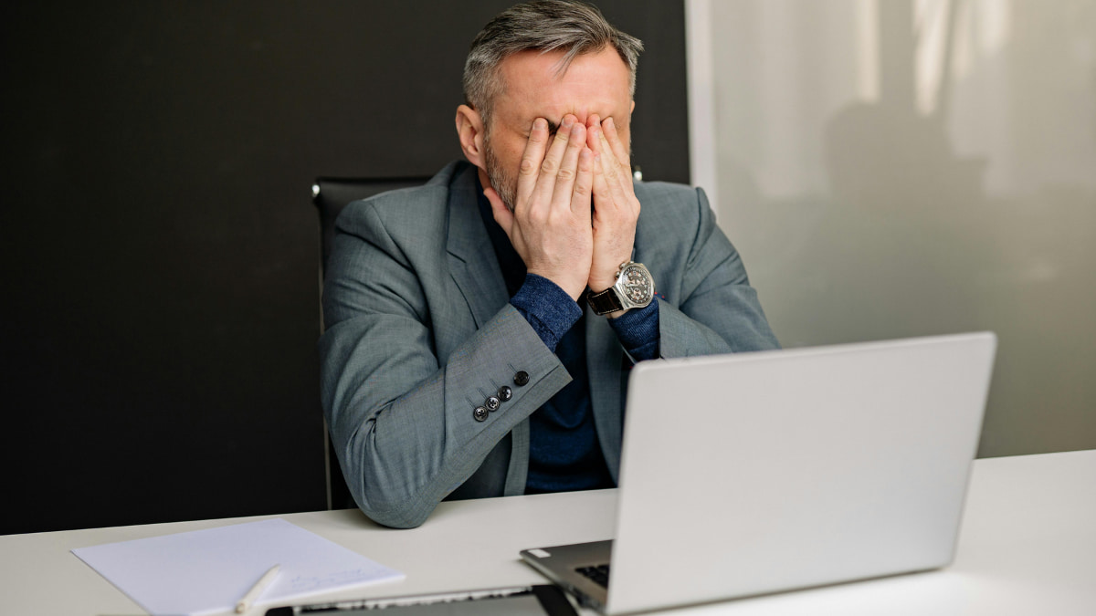 Homem preocupado no computador, ilustrando o impacto dos golpes financeiros alimentados por IA no ambiente digital.