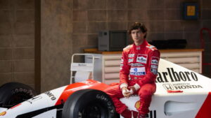 Gabriel Leone, ator da série sobre Ayrton Senna na Netflix, sentado em um Fórmula 1 da McLaren, recriando a era de ouro do piloto.