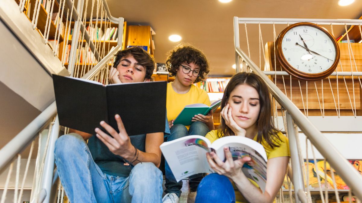 3 estudantes sentados na escada e lendo livros, representando as escolas mais caras do Brasil.