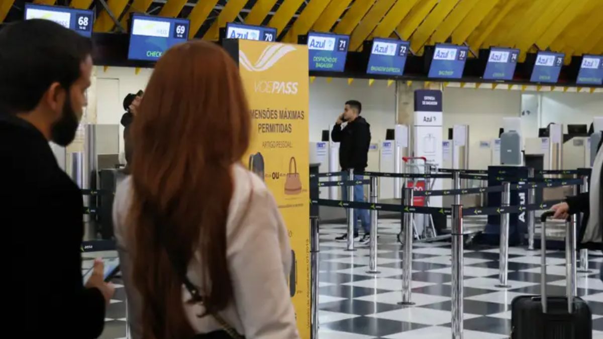 Pessoas passando no saguão do aeroporto.