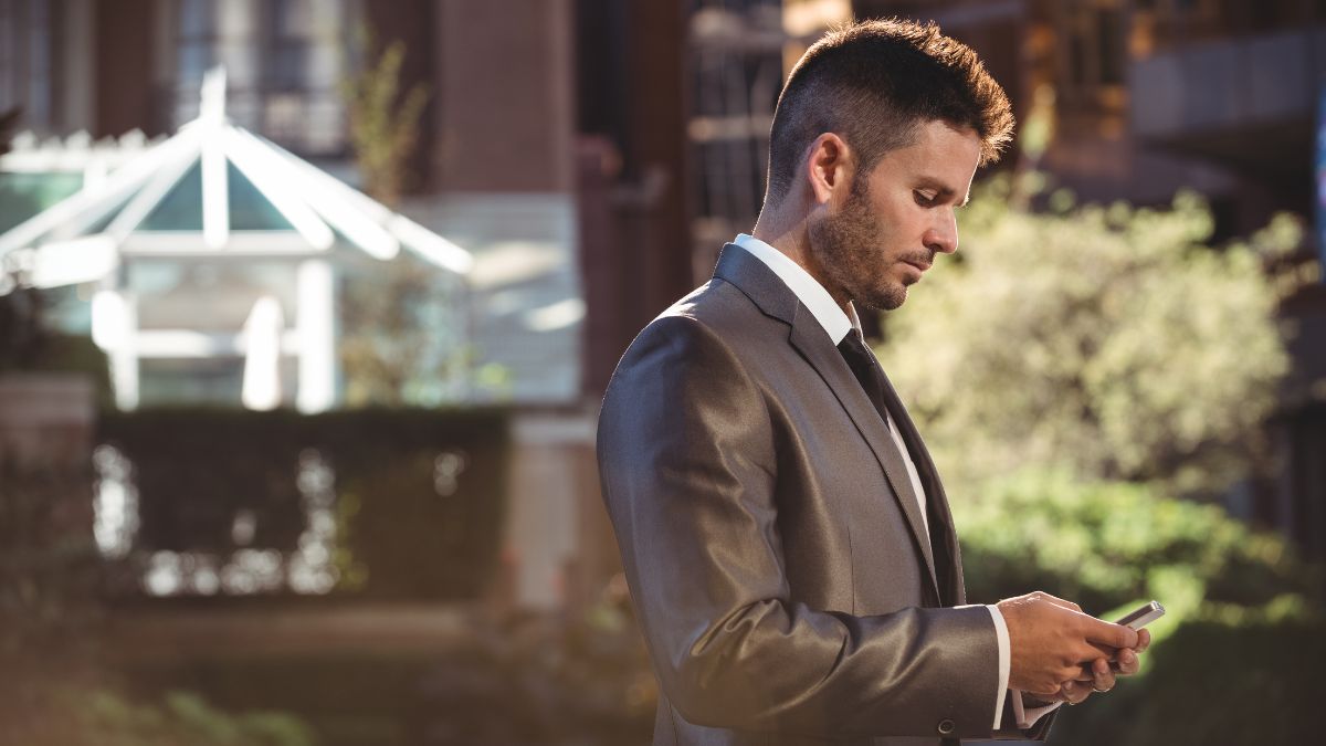 Homem de negócios mexendo no celular, representando quem é rico no Brasil.