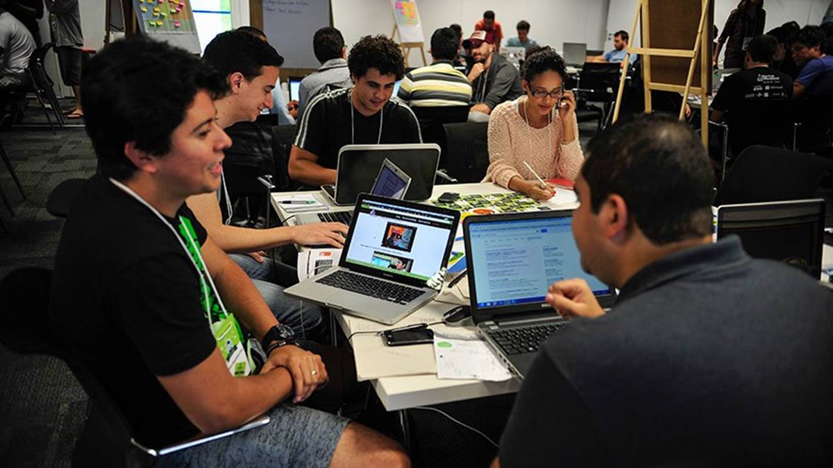 Na imagem, jovens estão à mesa com computadores. Pesquisa mostrou que A maioria dos jovens brasileiros se identificam com o empreendedorismo