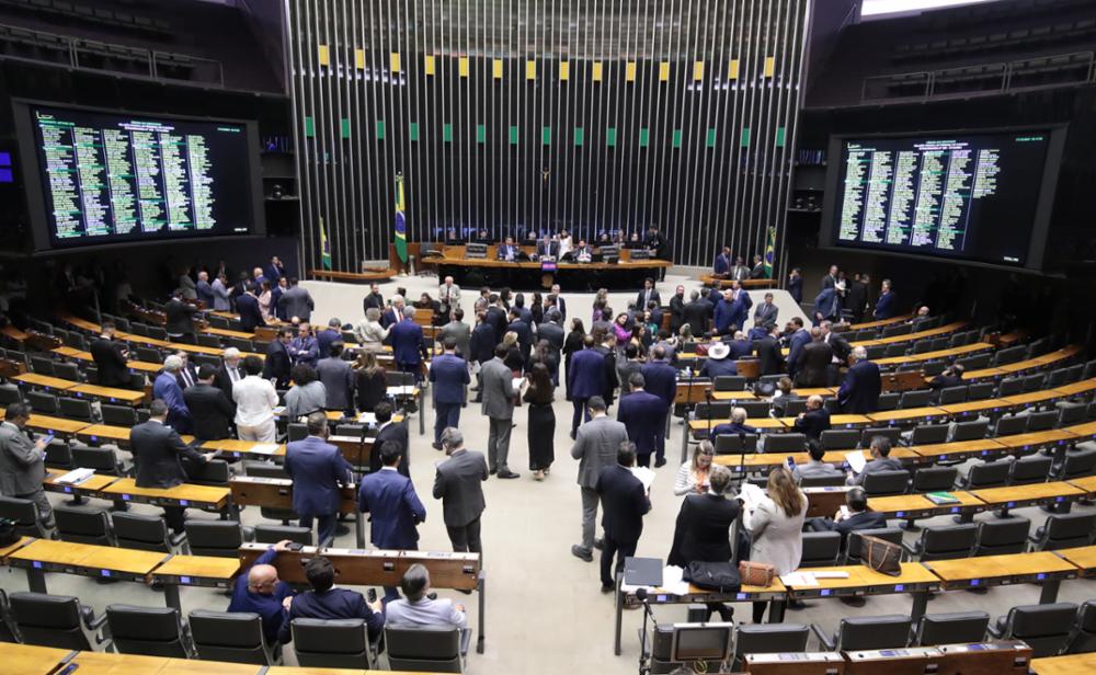 Na imgem, ao centro e sentado, Arthur Lira, presidente da Câmara dos Deputados, arrodeado de parlamentares após aprovação do texto da reforma tributária