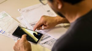 Na imagem um homem calculando contas em meio ao anúncio do Banco Central que haverá pagamentos de boletos via Pix