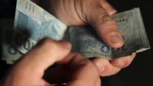 Imagem com notas de 100 reais sobrepostas, em meio a disputa entre bancos e governo sobre a taxa de juros consignada