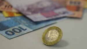Na imagem, notas de R$ 100 e R$ 5, além uma moeda de R$ 1,00. Gasto com juros da dívida pública bate novo recorde