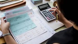 Imagem de uma calculadora e contas sobre a mesa. Inadimplência das empresas bate recorde, e dívidas disparam