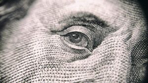 Close-up detalhado do olho em uma nota de dólar, destacando os traços e padrões finos da impressão.
