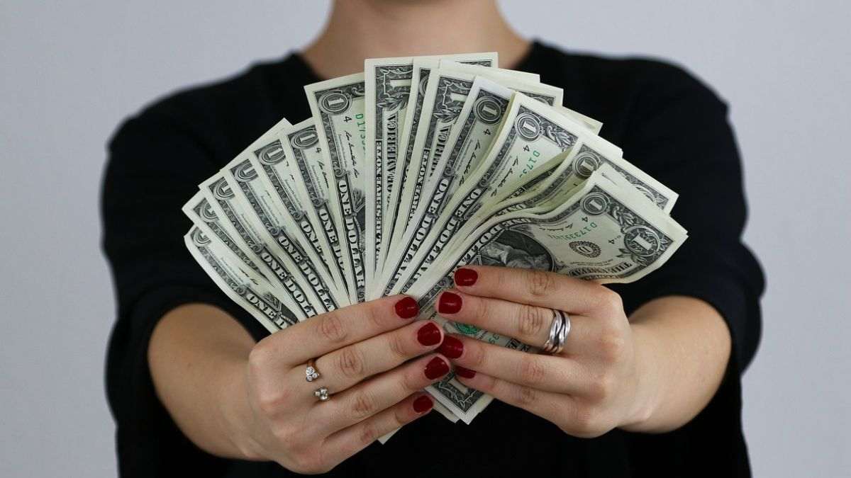 Imagem de uma mulher segurando dinheiro para ilustrar uma matéria jornalística sobre os maiores salários no Brasil