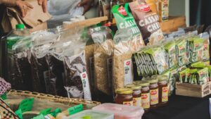 Exposição de produtos naturais e sustentáveis em embalagens eco-friendly, incluindo arroz integral, chips de mandioca e mel artesanal, em um supermercado.