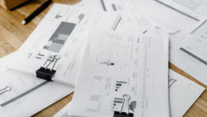 Documentos e gráficos financeiros impressos em mesa de madeira, representando relatórios de reembolsos corporativos e análises de despesas.