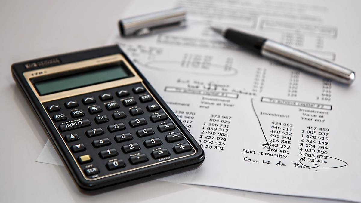 Na imagem consta uma calculadora, uma caneta e uma fatura com valores. Regulamentação do CMN aprova uso de imóvel para mais de um financiamento