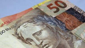 Na imagem consta uma cédula de 50 sobreposta a uma de 20, em alusão ao resultada da poupança de novembro
