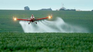 Imagem de um monomotor distribuindo fertilizantes em uma plantação. Saiba como lobby do agro obteve isenção para agrotóxicos na reforma tributária