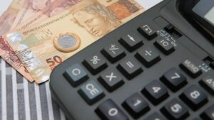 Imagem com calculadora e notas sobre a mesa. Títulos públicos atrelados à Selic tiveram alta em novembro