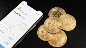 Criptomoedas em um celular, com moedas ao lado.