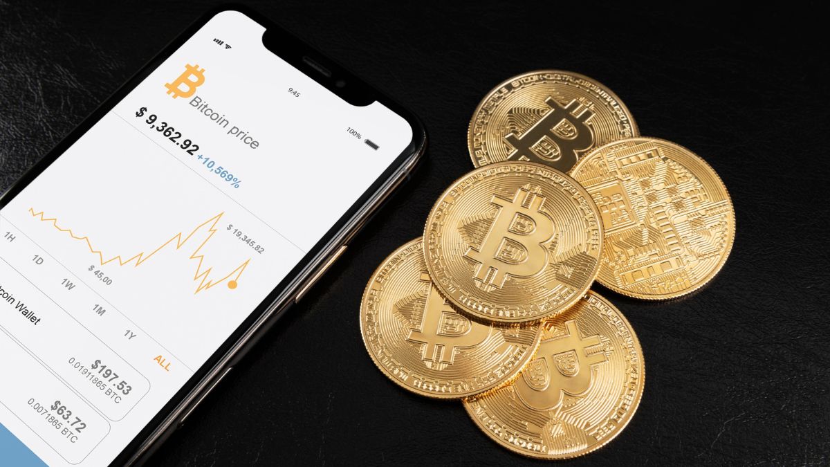 Criptomoedas em um celular, com moedas ao lado.
