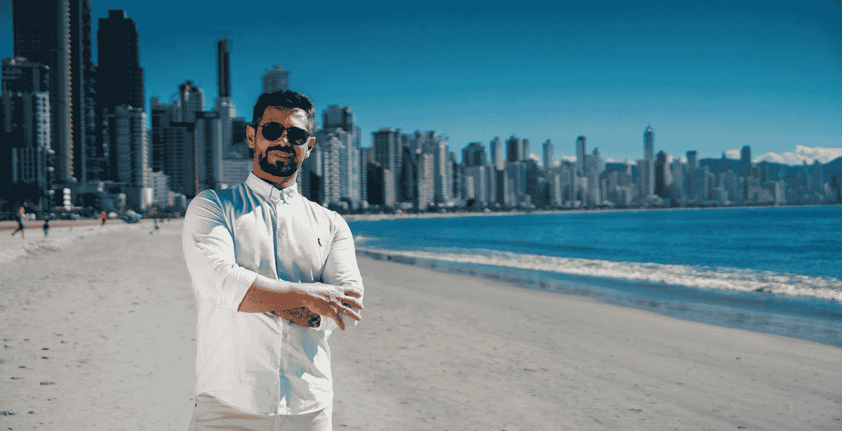 Especialista Bruno Cassola em Balneário Camboriú, com arranha-céus e praia ao fundo, representando o mercado imobiliário de Santa Catarina.