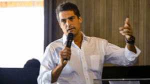 Celso Colombo Neto, empresário brasileiro e sócio da Carpa Family Office, falando ao público com microfone em mãos.