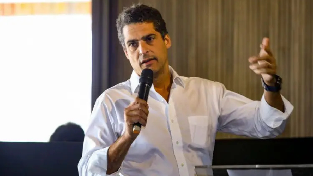 Celso Colombo Neto, empresário brasileiro e sócio da Carpa Family Office, falando ao público com microfone em mãos.