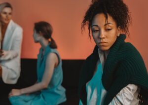Mulher com expressão de tristeza, destacando a exclusão e discriminação de gênero em um ambiente social ou profissional.