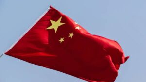 Imagem com a bandeira trêmula da China. Exportações da China crescem mais de 10% em dezembro de 2024