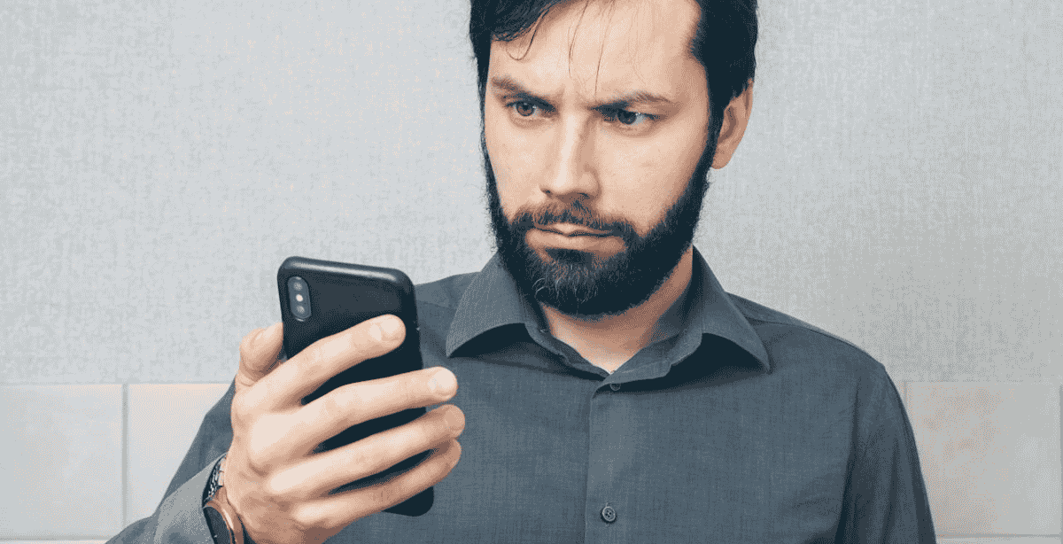 Homem olhando preocupado para o celular, representando alerta sobre golpes financeiros com Pix.