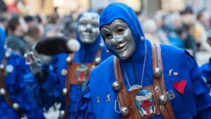 Homem mascarado em fantasia azul durante as festividades de Carnaval, representando a cultura e o cuidado necessário para evitar golpes no Carnaval.