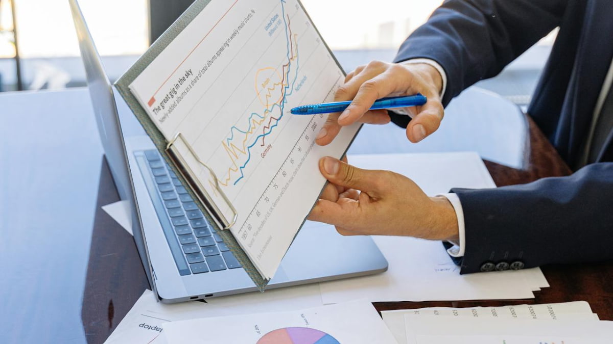 Profissional de terno explicando gráficos financeiros em uma prancheta, representando o papel do CFO no monitoramento de desempenho financeiro.