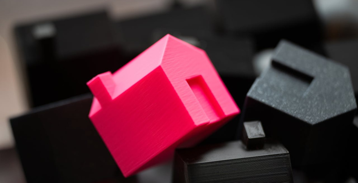 Miniatura de casa rosa destacada entre casas escuras, simbolizando o impacto do pedido de falência da Gafisa no mercado imobiliário.