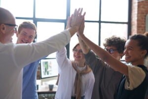 Equipe celebrando sucesso no trabalho em equipe, mostrando união e liderança em ambiente colaborativo.