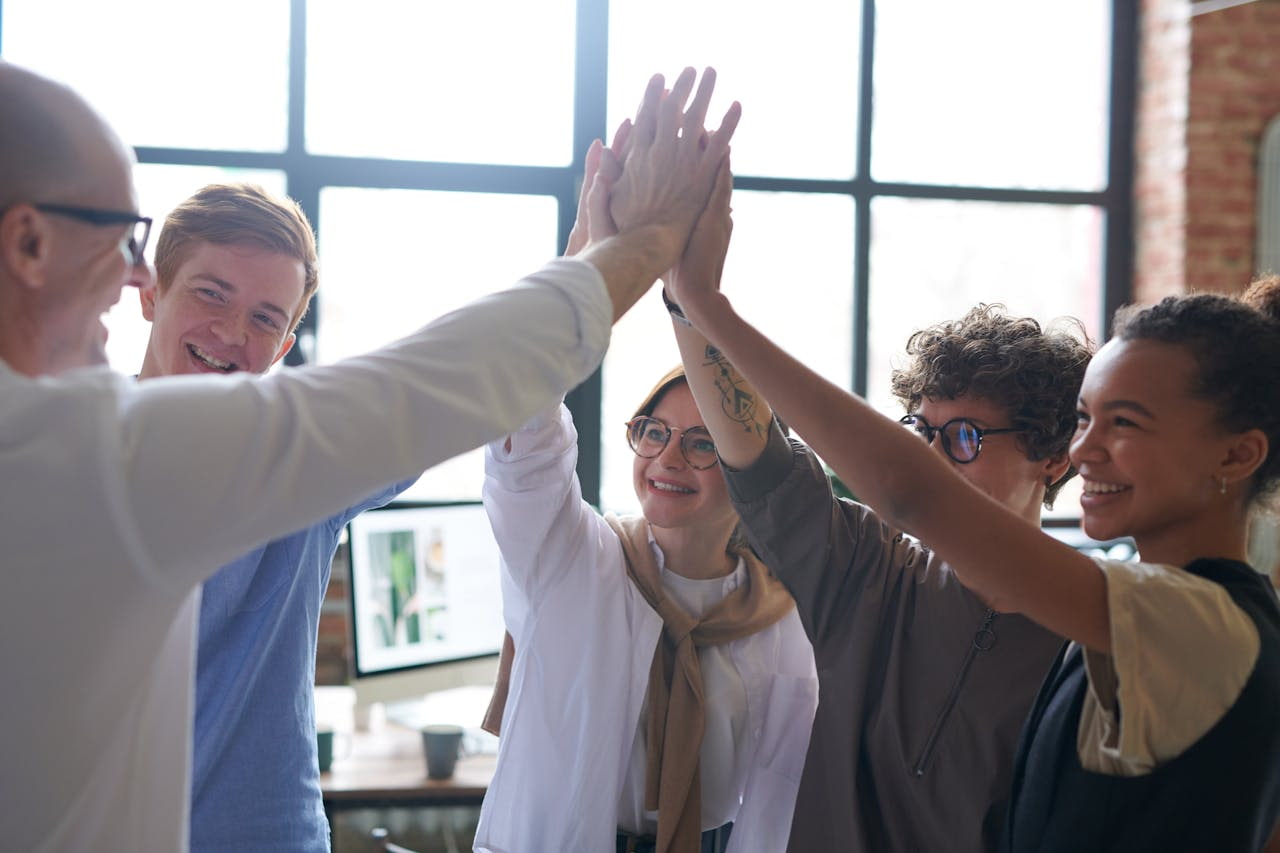 Equipe celebrando sucesso no trabalho em equipe, mostrando união e liderança em ambiente colaborativo.