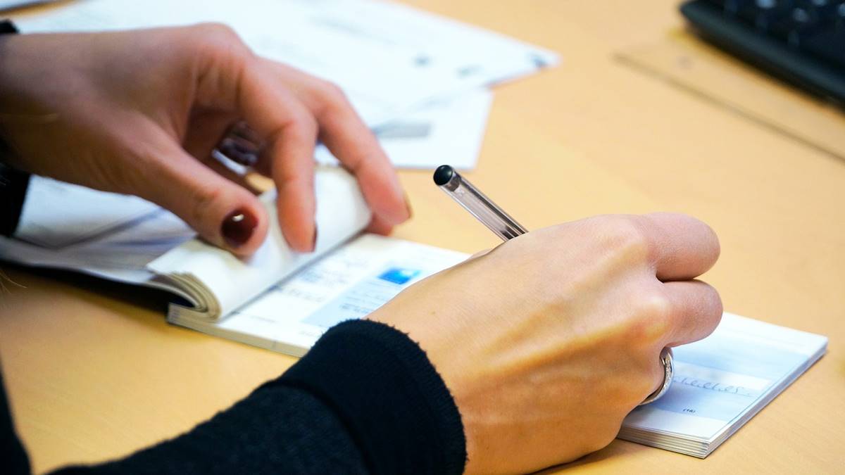 Imagem de um cheque sendo assinado. Uso de cheque representa apenas 0,5% das movimentações financeiras