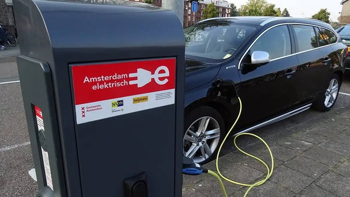 Imagem de um carro elétrico preto sendo carregado. Venda de veículos elétricos quase dobra em 2024