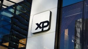 Imagem da logo da XP Investimentos para ilustrar uma matéria jornalística sobre projeções econômicas para 2025.