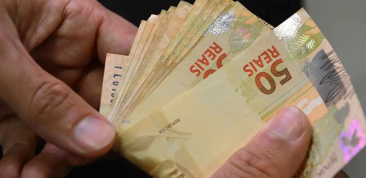 Mãos contam dinheiro em referência a economizar no IPVA