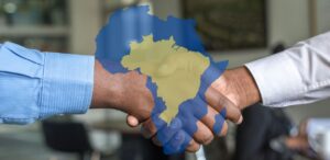 Aperto de mãos entre empresários, com sobreposição dos mapas do Brasil e da África, simbolizando o fortalecimento das relações Brasil e África.