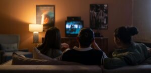 Pessoas assistem TV em uma sala aconchegante, refletindo o impacto das empresas de streaming no entretenimento.